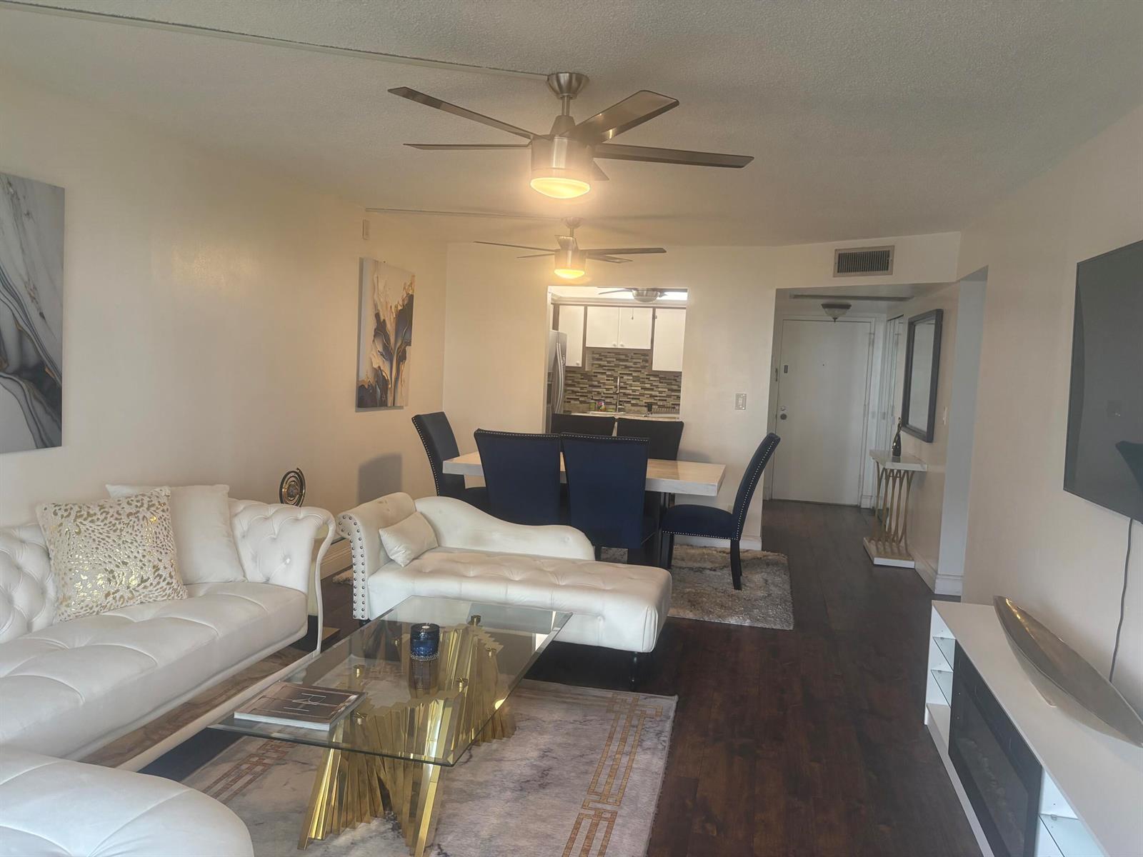 A living room and dining area feature white tufted furniture, a glass coffee table, and dark flooring — 9355 SW 8th Street # 225, Boca Raton FL 33428, BOCA RATON, FL