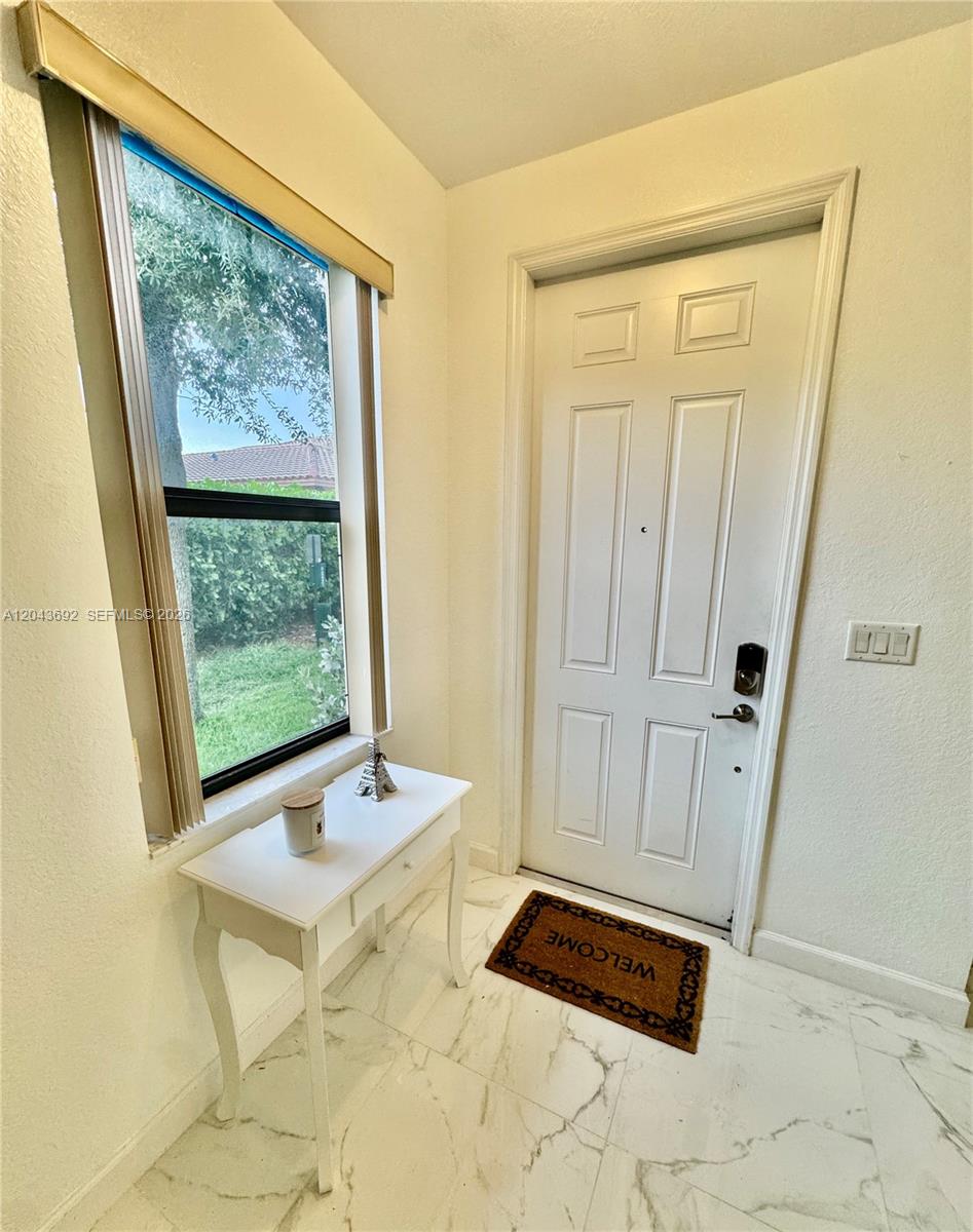 An entryway features a white door, a window, a small table, and marble-look tile flooring — 8805 W 35th Ave, Hialeah FL 33018, HIALEAH, FL