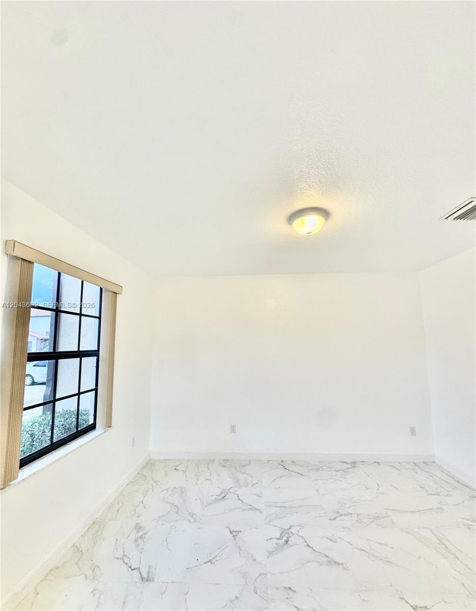An empty room features white walls, a single window, and white marble-patterned tile flooring — 8805 W 35th Ave, Hialeah FL 33018, HIALEAH, FL