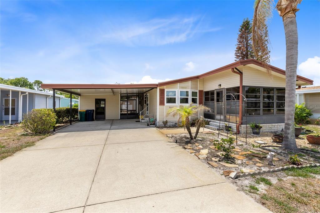 A single-story manufactured home with a concrete driveway, carport, and a screened-in front porch — 3217 RAINBOW ROAD, TAVARES, FL