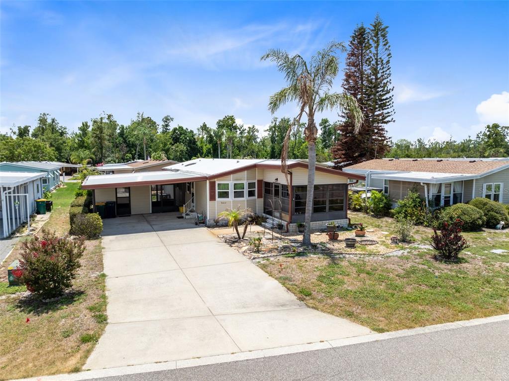 A single-story manufactured home with a concrete driveway, carport, and a screened-in front porch — 3217 RAINBOW ROAD, TAVARES, FL