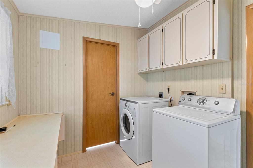 A laundry room features a washer, dryer, upper cabinets, and a folding counter — 3217 RAINBOW ROAD, TAVARES, FL