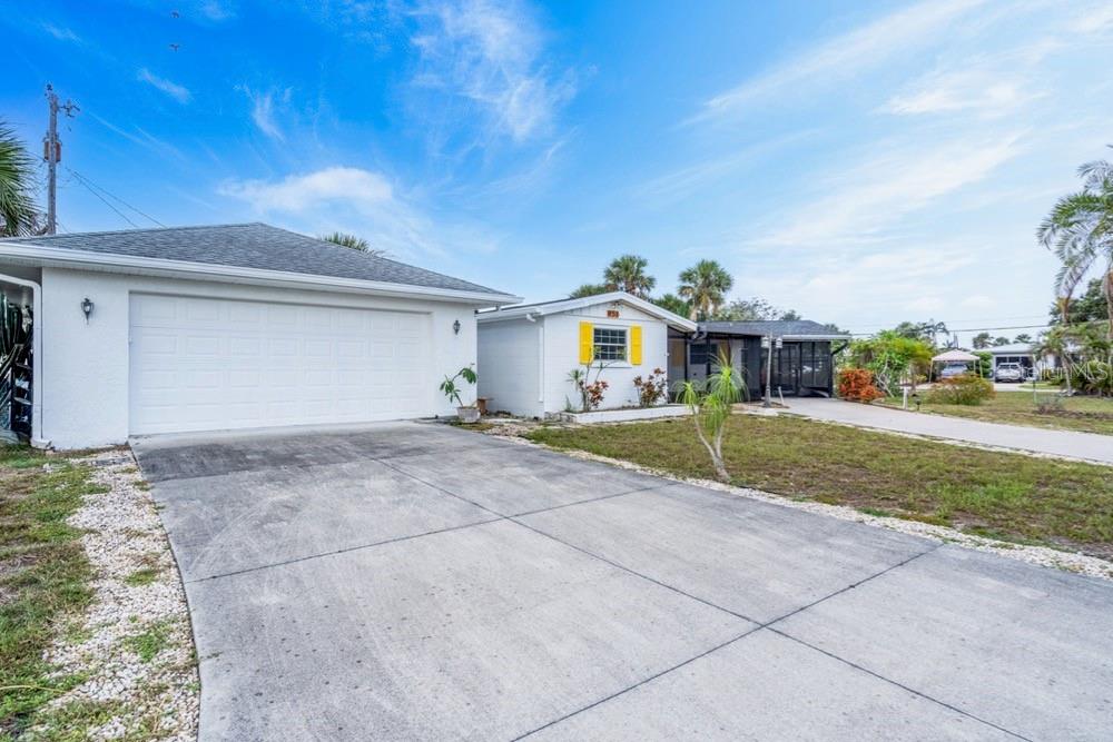 A white house with a concrete driveway and a two-car garage under a blue sky — 456 SANDLEWOOD DRIVE, VENICE, FL