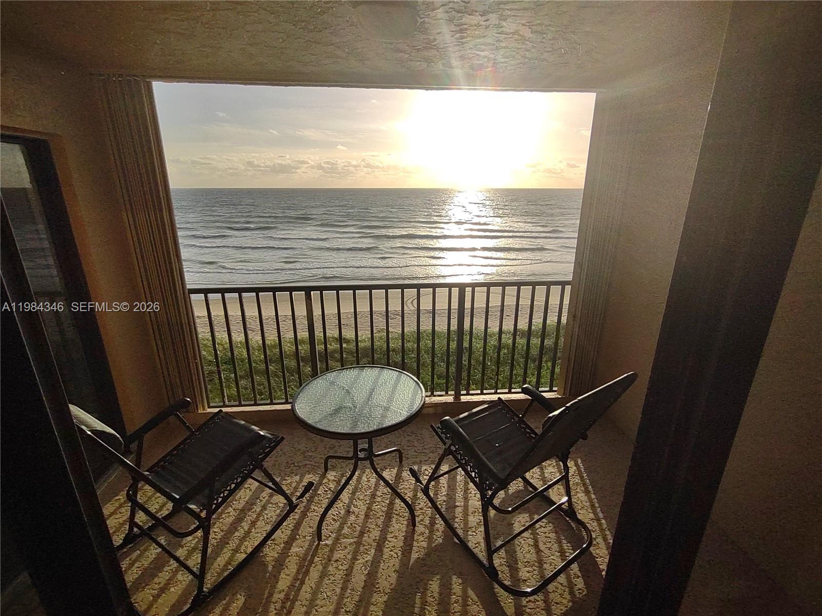 A balcony features two rocking chairs and a small table overlooking the ocean at sunset — 10200 S Ocean Dr # 504, Jensen Beach FL 34957, JENSEN BEACH, FL