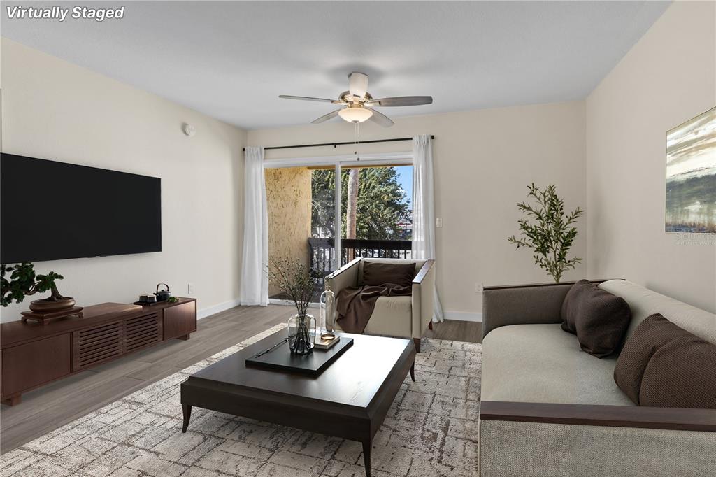 A living room with a television, sofa, armchair, coffee table, and a sliding glass door — 3405 CLARK ROAD UNIT 205, SARASOTA, FL