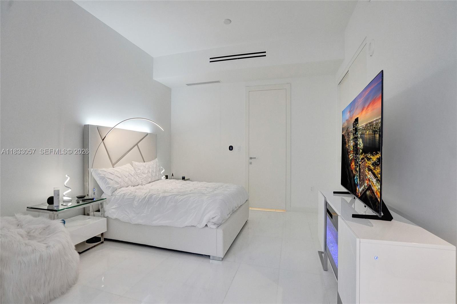 A modern white bedroom features a platform bed, a glass side table, and a television — 300 Biscayne Blvd Way # 505C, Miami FL 33131, MIAMI, FL