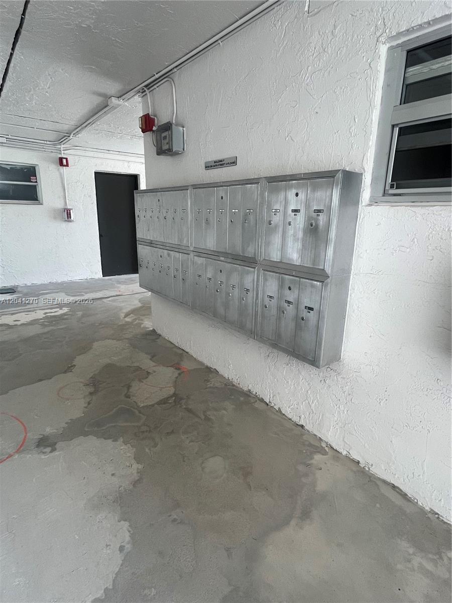 A set of metal mailboxes is mounted on a white wall in a concrete hallway — 14170 SW 84th St # F, Miami FL 33183, MIAMI, FL