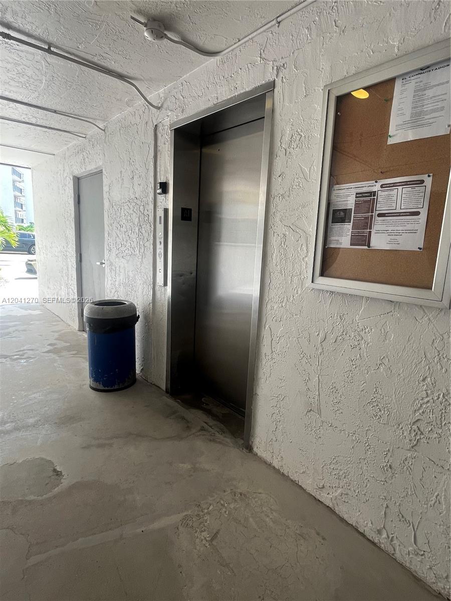 A stainless steel elevator sits next to a bulletin board and a blue trash can — 14170 SW 84th St # F, Miami FL 33183, MIAMI, FL