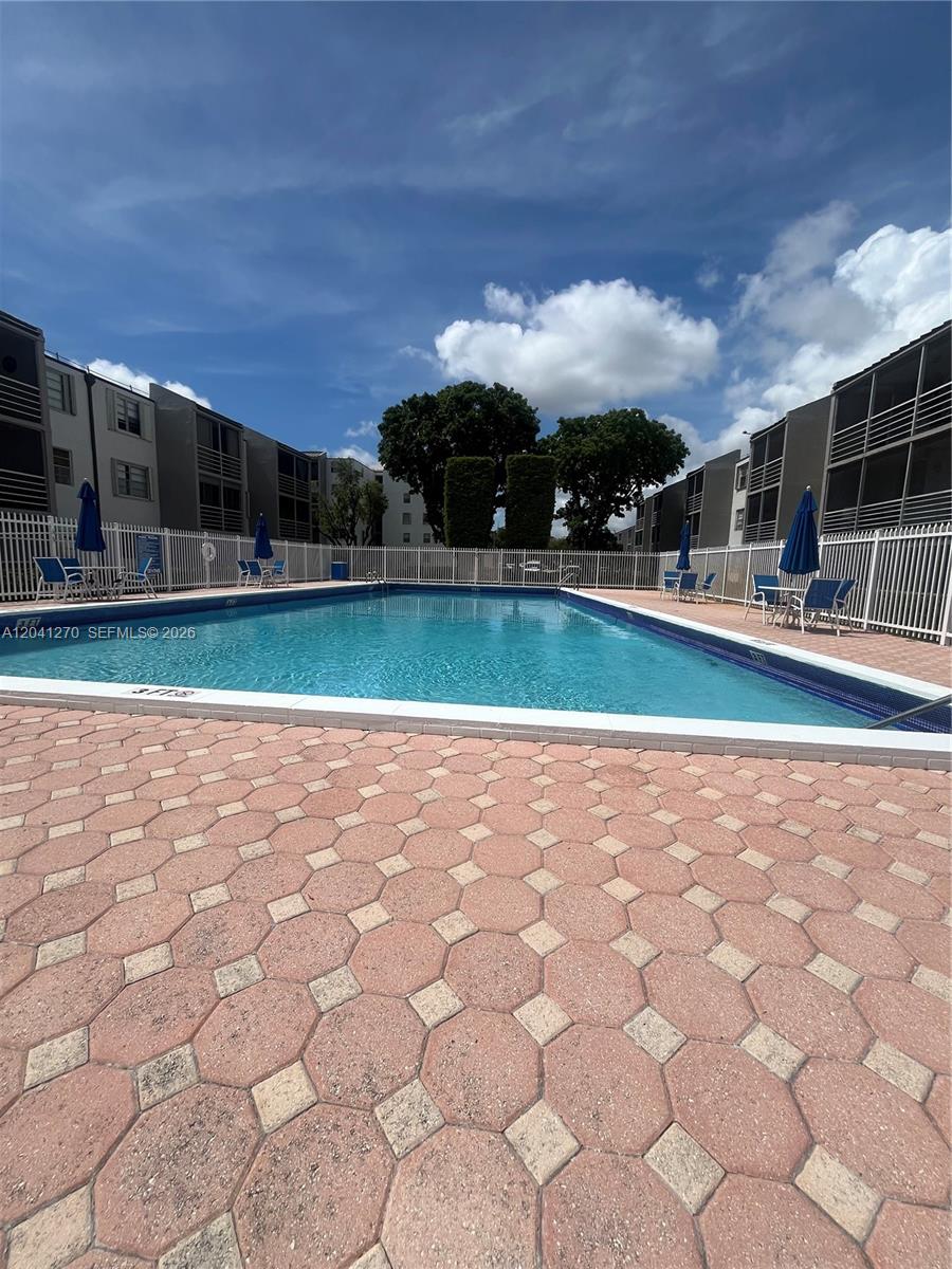 A rectangular swimming pool is surrounded by a paved deck and residential apartment buildings — 14170 SW 84th St # F, Miami FL 33183, MIAMI, FL