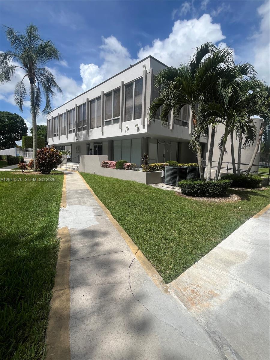 A two-story building with large windows and palm trees sits next to a concrete walkway — 14170 SW 84th St # F, Miami FL 33183, MIAMI, FL
