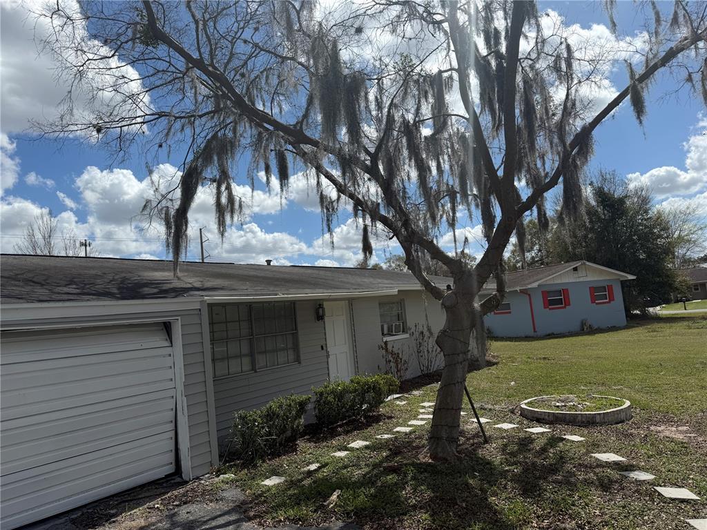 A single-story house with gray siding and a garage sits behind a large mossy tree — 2105 SW 38TH COURT, OCALA, FL