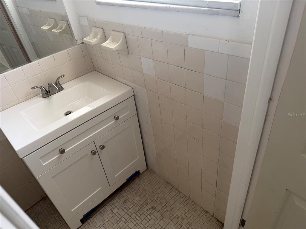 A bathroom features a white vanity, a tiled wall, and a small mosaic floor — 2105 SW 38TH COURT, OCALA, FL