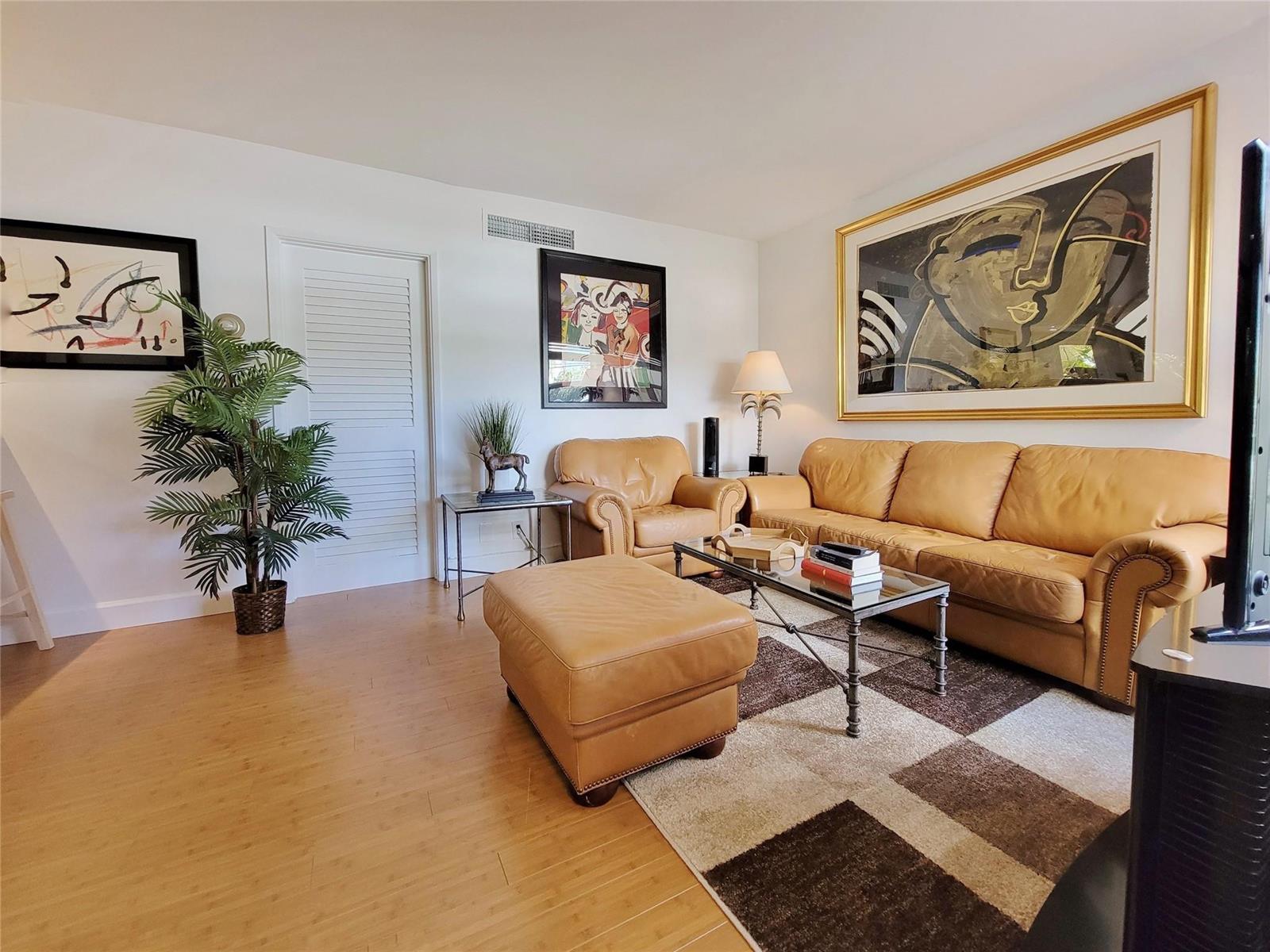A living room features tan leather furniture, a glass coffee table, and large framed artwork — FORT LAUDERDALE, FL