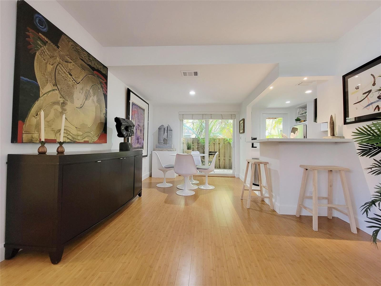 A dining area and kitchen breakfast bar feature white walls, bamboo flooring, and modern furniture — FORT LAUDERDALE, FL