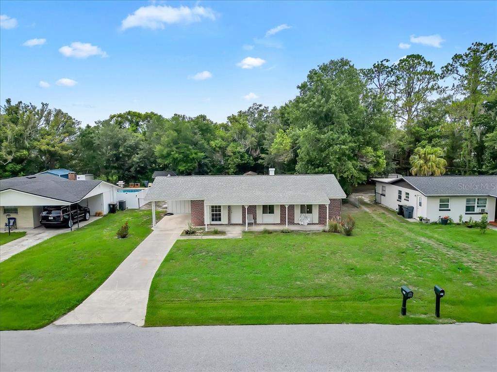 An exterior view of a single-story brick and siding house with a front lawn — 5810 DRIFTWOOD DRIVE, LAKELAND, FL