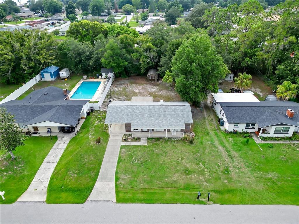 An aerial view shows three suburban houses with driveways, a swimming pool, and trees — 5810 DRIFTWOOD DRIVE, LAKELAND, FL