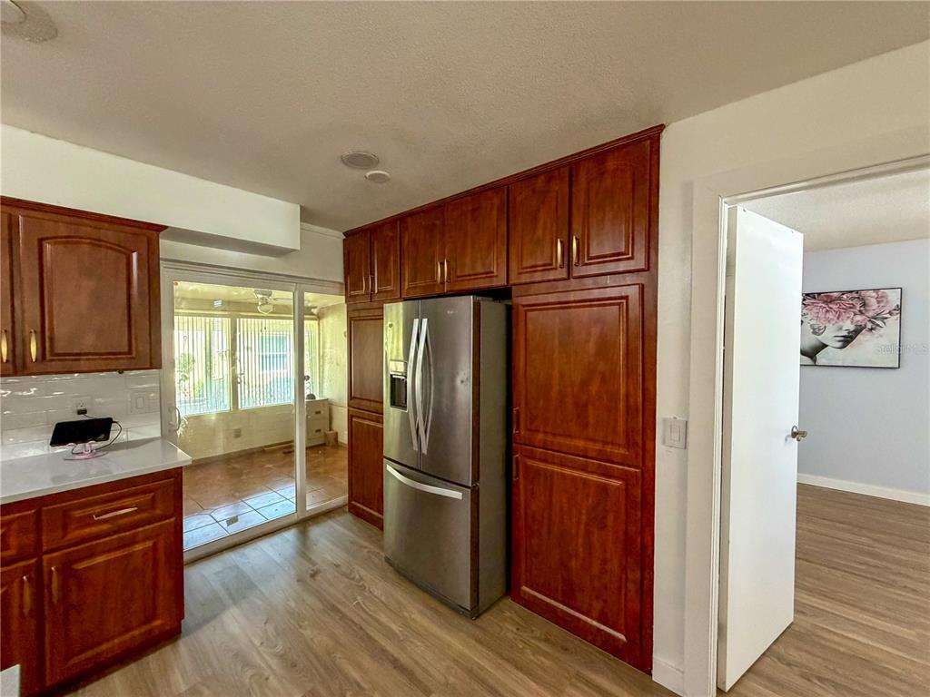A kitchen features wood cabinets, stainless steel appliances, and a sliding door to a sunroom — 45 CASWELL DRIVE, ORLANDO, FL