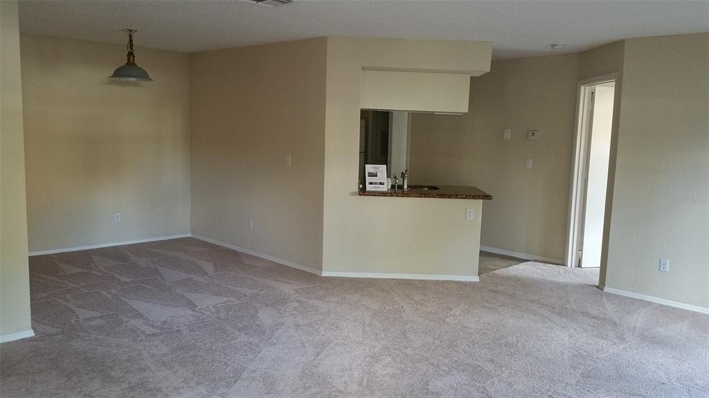 An interior view shows a carpeted living area with a pass-through kitchen counter — 2550 N ALAFAYA TRAIL UNIT 7104, ORLANDO, FL