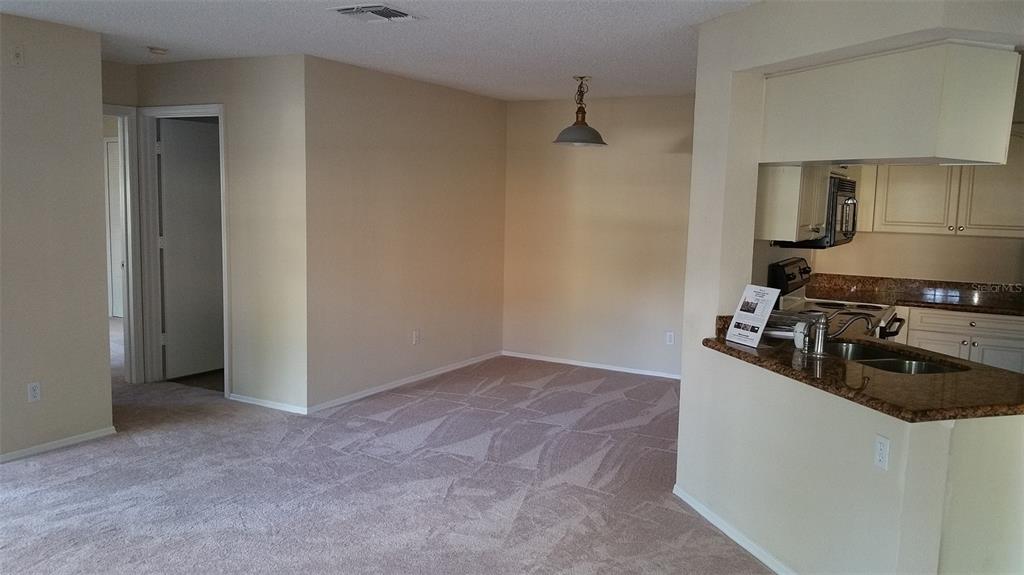 A carpeted dining area sits adjacent to a kitchen with granite countertops and white cabinets — 2550 N ALAFAYA TRAIL UNIT 7104, ORLANDO, FL