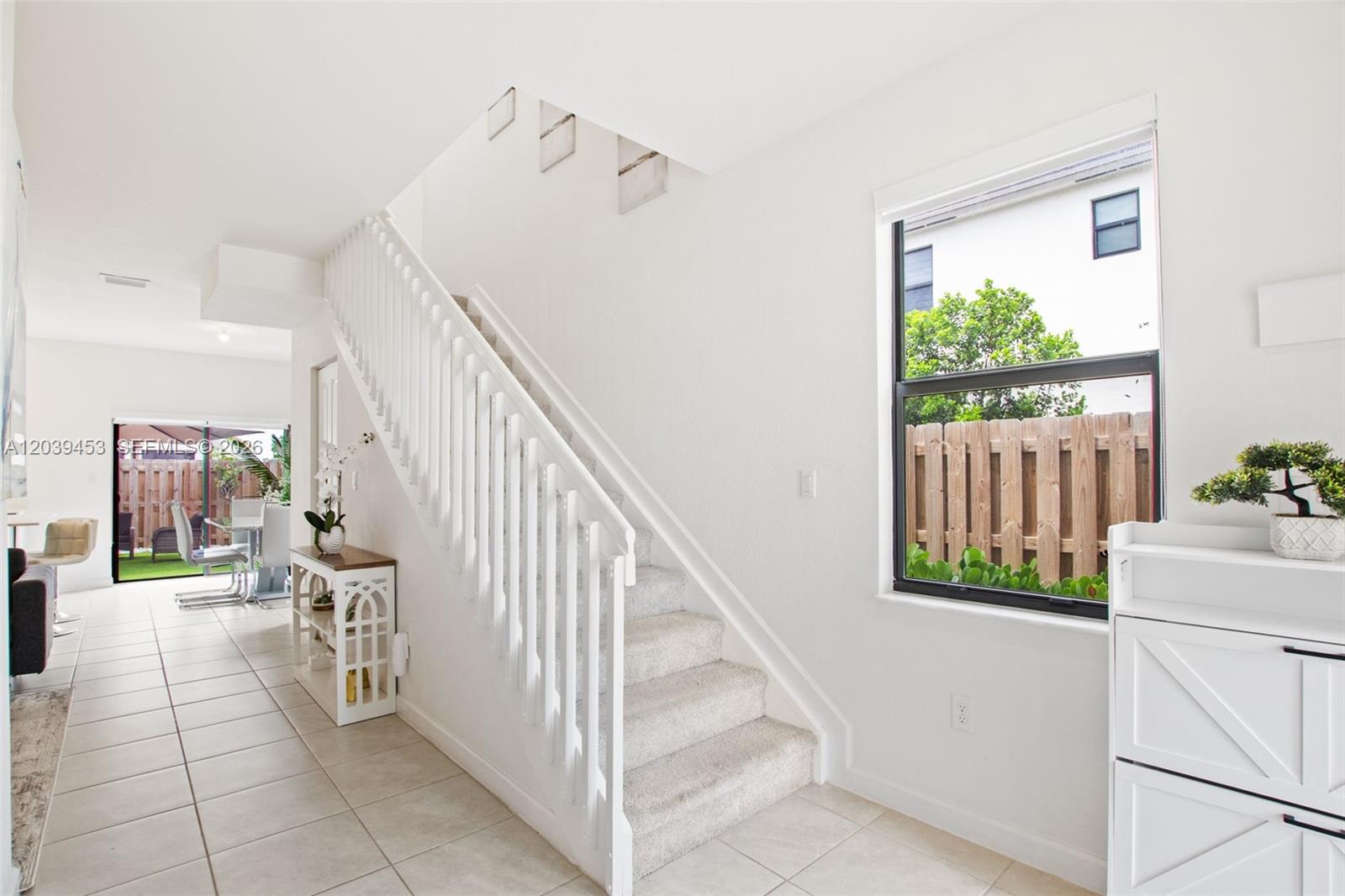 A staircase with white railings and carpeted steps sits in a bright, tiled entryway — 23391 SW 128th Ave, Homestead FL 33032, HOMESTEAD, FL