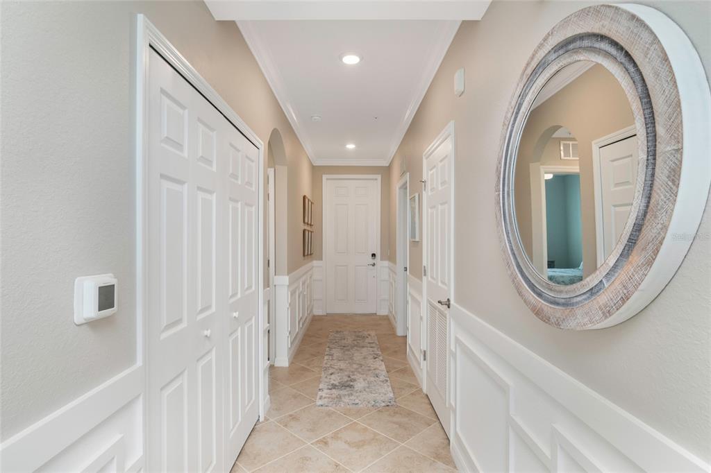 A hallway features tile flooring, white wainscoting, a round mirror, and several white doors — 14051 HERITAGE LANDING BOULEVARD UNIT 523, PUNTA GORDA, FL