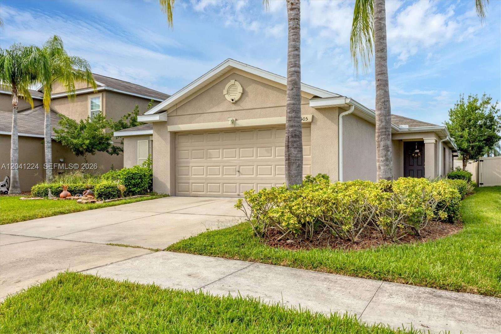 A single-story beige house features a two-car garage, a front entrance, and palm trees — 16505 Myrtle, Tampa FL 33598, TAMPA, FL