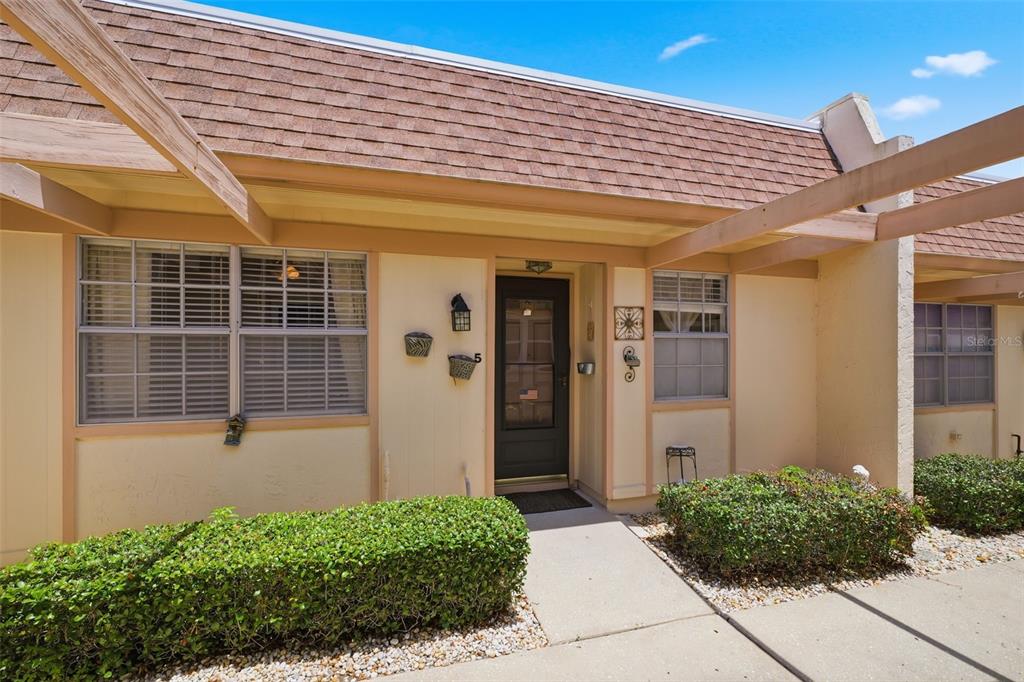 A single-story residential unit exterior with a brown shingled roof, beige walls, and landscaping — 11210 CARRIAGE HILL DRIVE UNIT 5, PORT RICHEY, FL