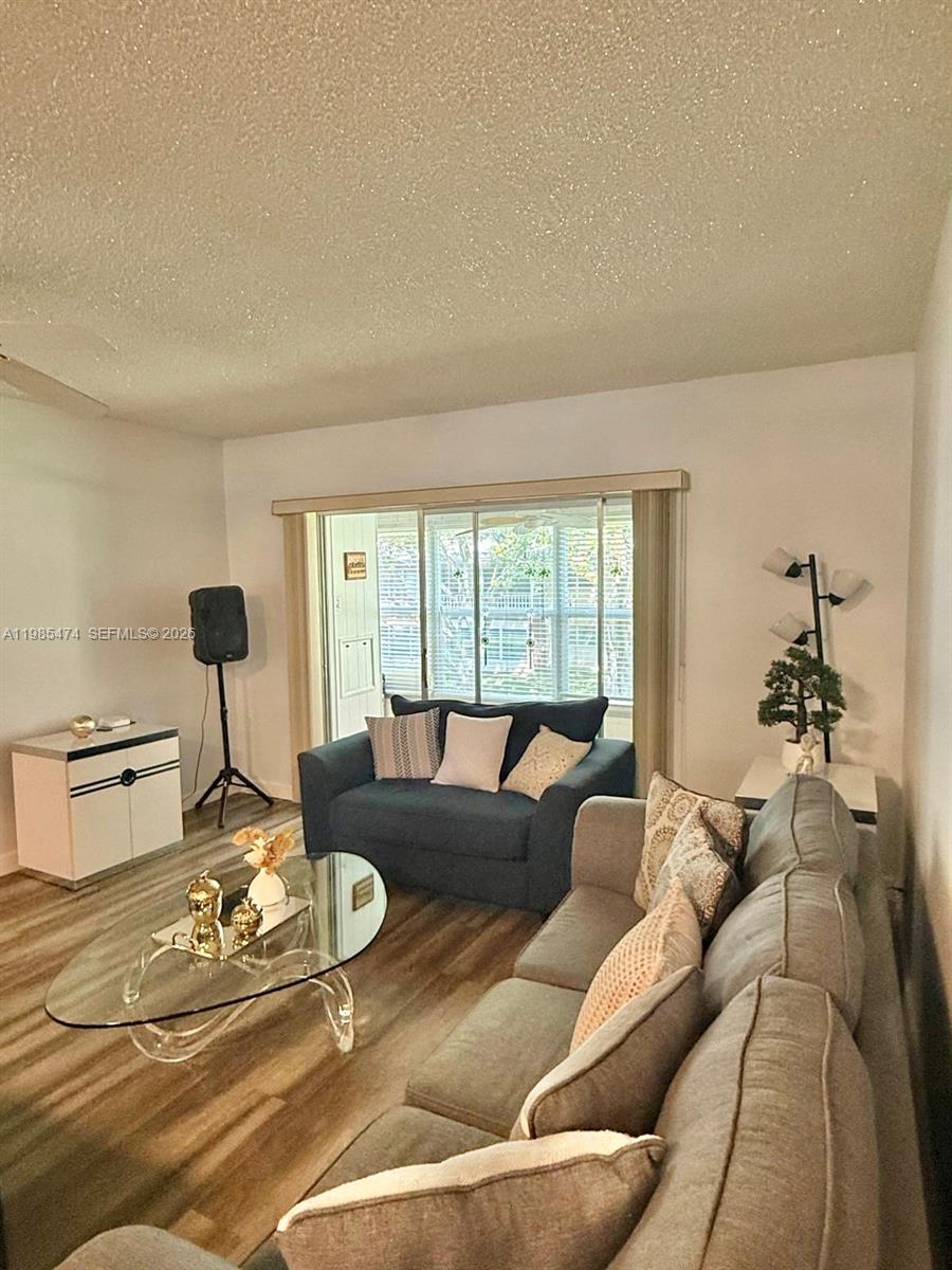 A living room features a gray sofa, a dark loveseat, and a glass coffee table — 7605 W Atlantic Blvd # 207, Margate FL 33063, MARGATE, FL