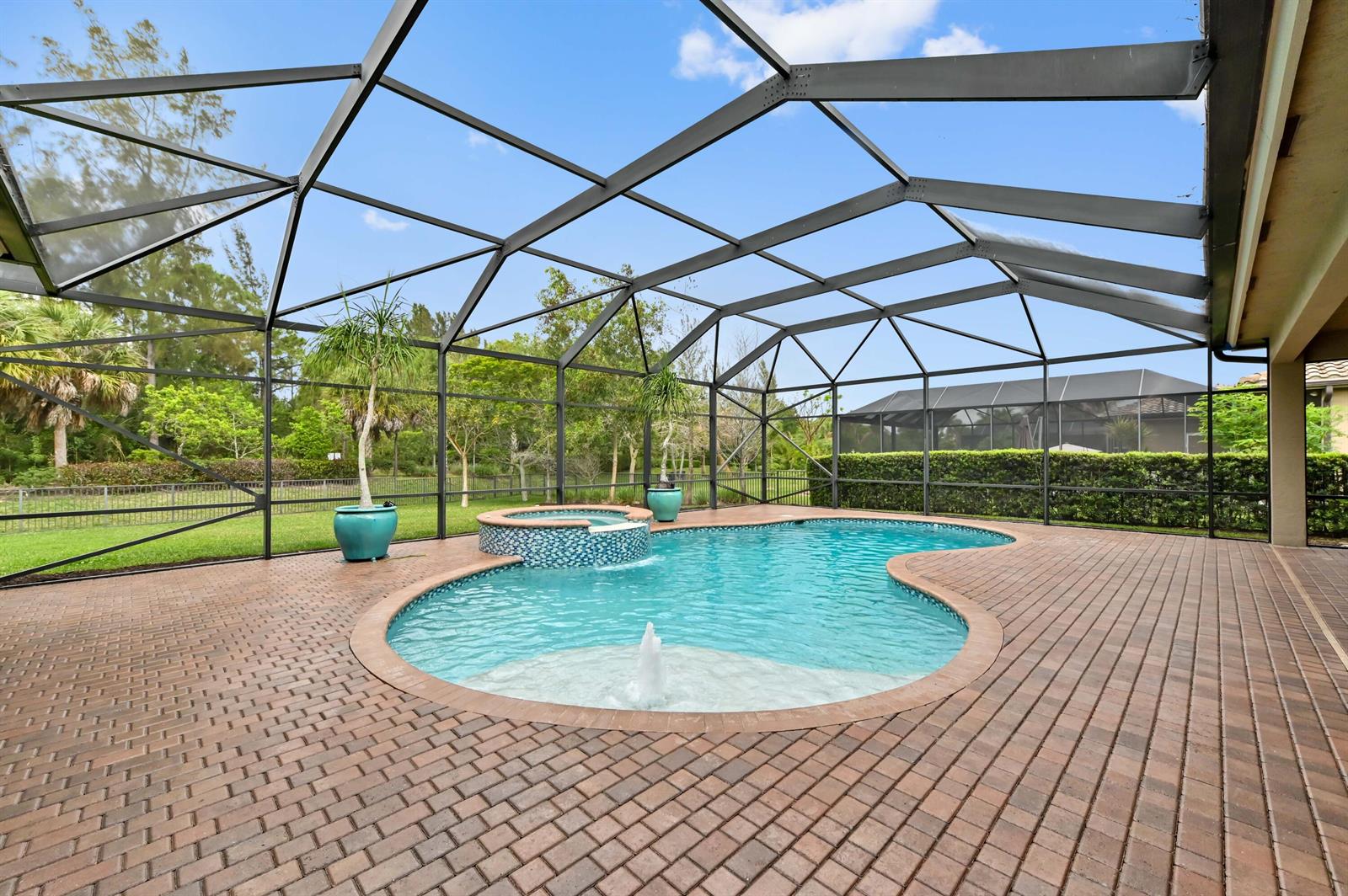 A screened-in patio features a brick-paver deck, a swimming pool with a fountain, and a spa — 7777 Eden Ridge Way, West Palm Beach FL 33412, WEST PALM BEACH, FL