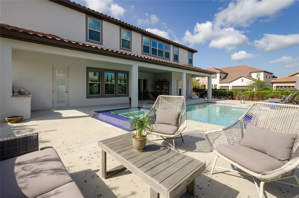 A patio with a pool, spa, and outdoor furniture sits behind a two-story house — 8539 PIPPEN DRIVE, ORLANDO, FL