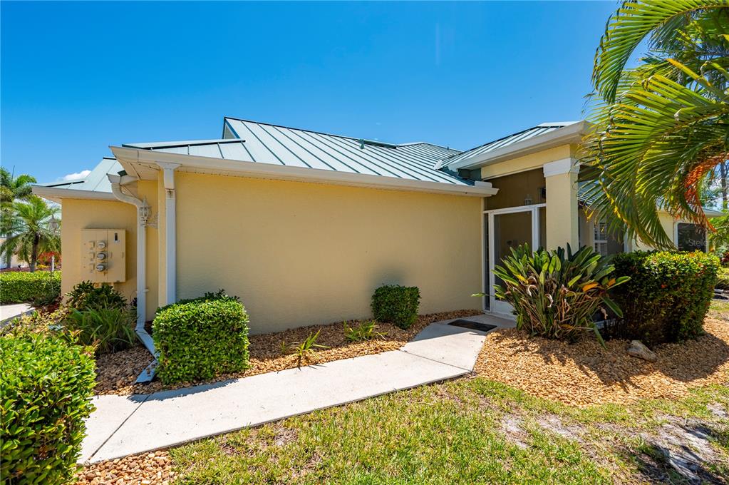 A concrete walkway leads to the screened front entryway of a yellow stucco house — 310 ISLAMORADA BOULEVARD, PUNTA GORDA, FL