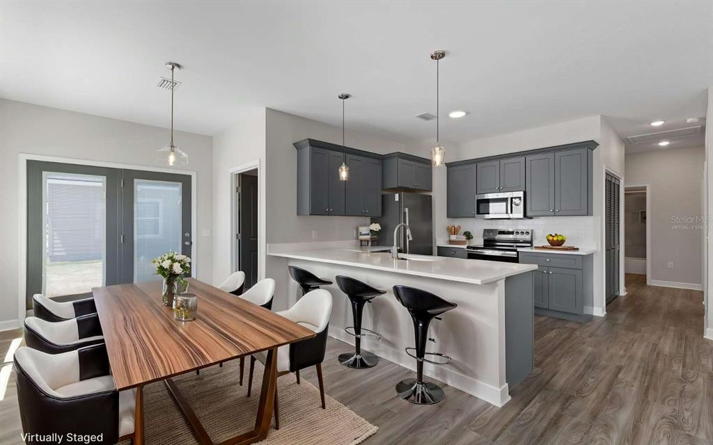 A kitchen with gray cabinets, a white island, and a dining table with chairs — 206 MESA STREET NW, LIVE OAK, FL