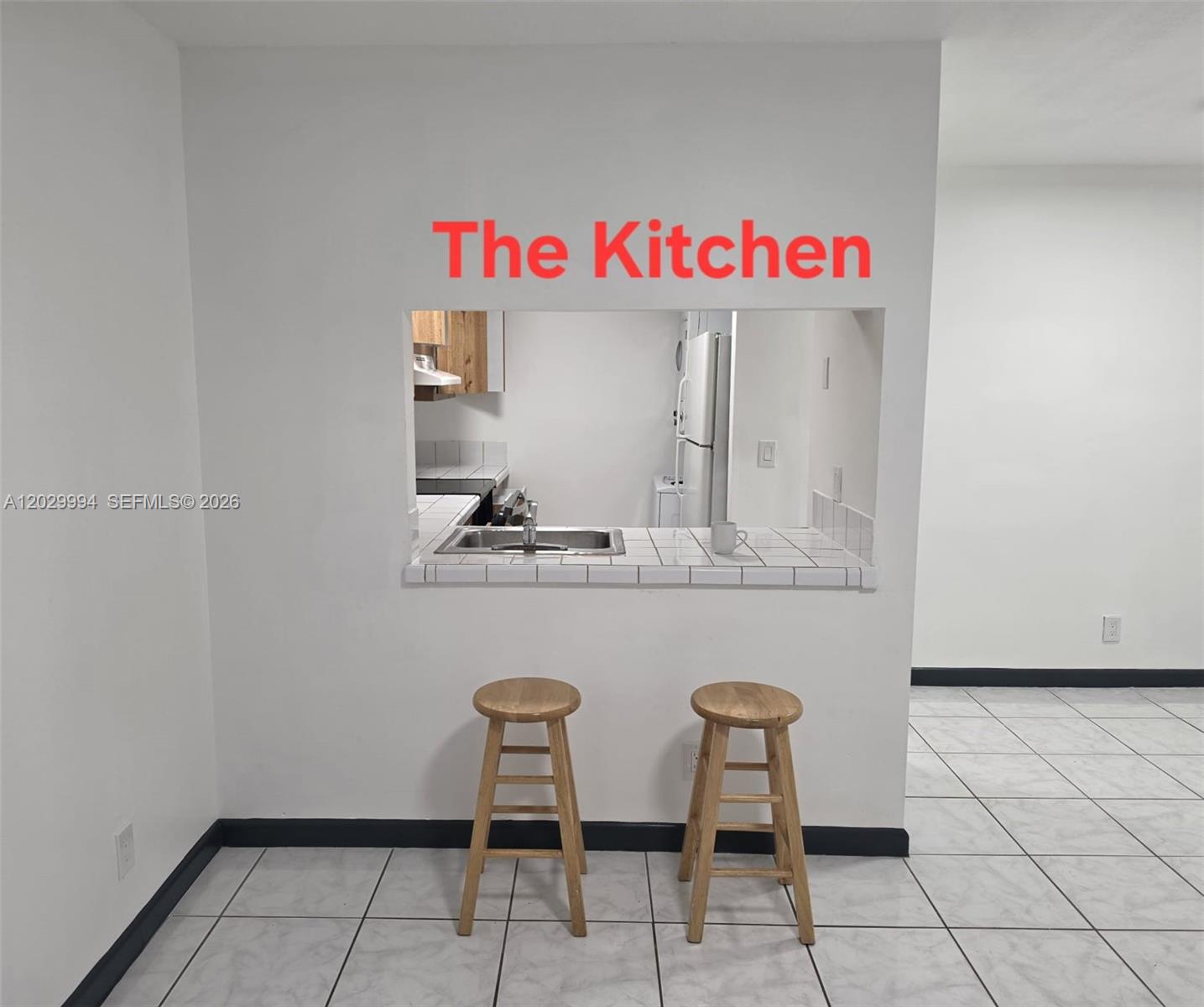 A kitchen pass-through window with a tiled counter and two wooden stools — SUNRISE, FL