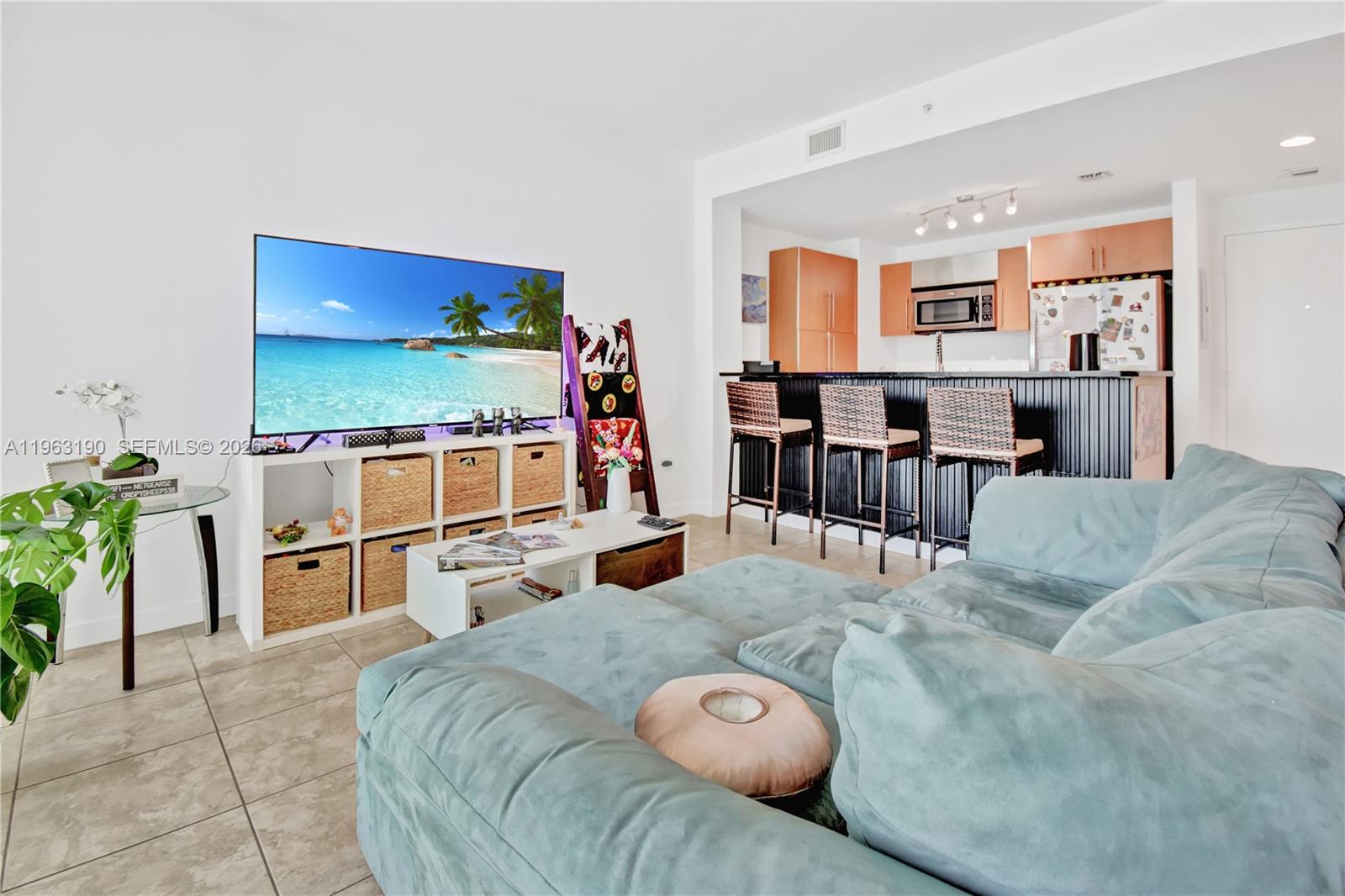 A living room with a large television, white shelving, and a kitchen with bar seating — 300 S Biscayne Blvd # 1405, Miami FL 33131, MIAMI, FL