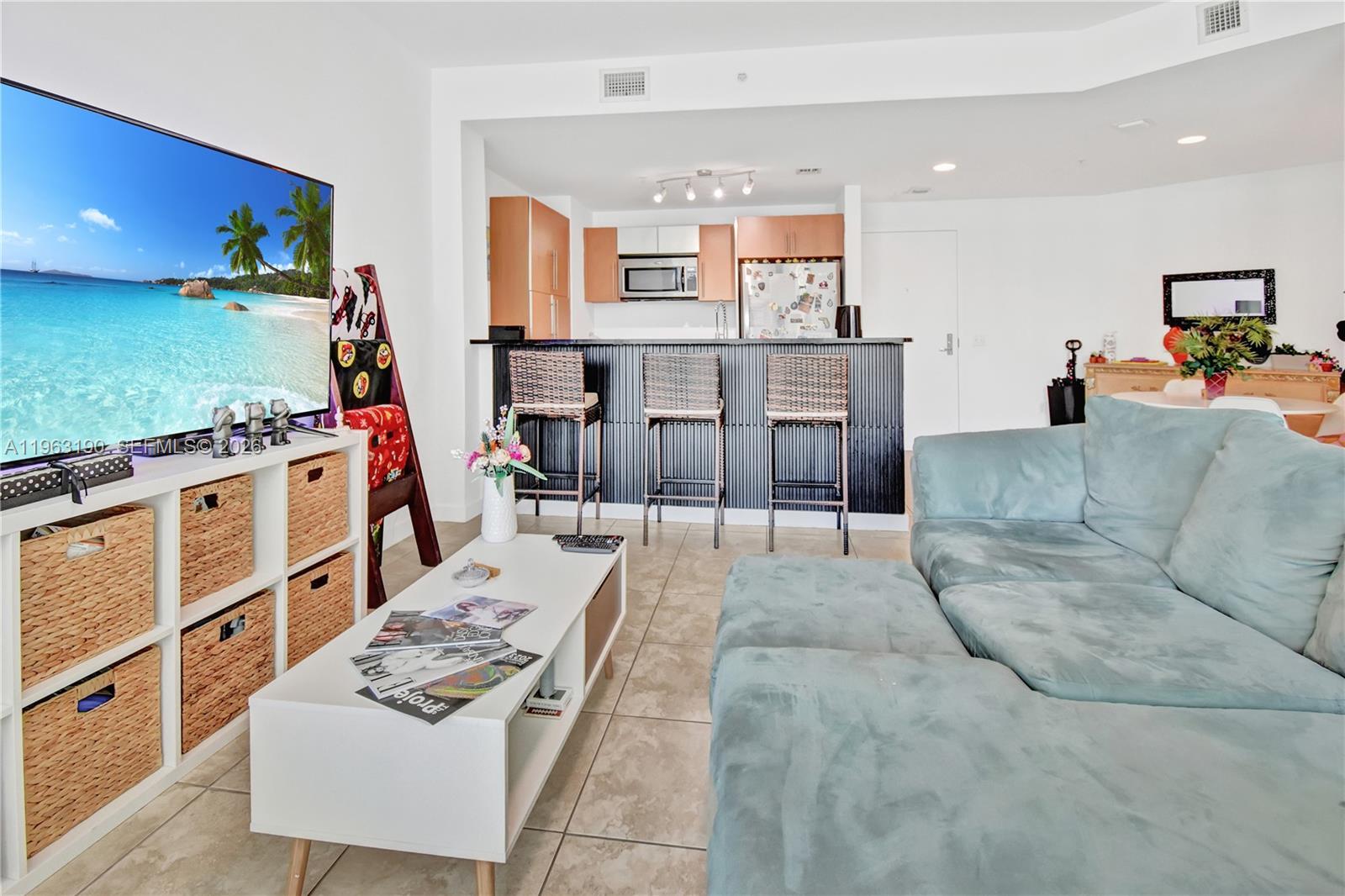 A living room features a light blue sectional sofa, a white coffee table, and a kitchen — 300 S Biscayne Blvd # 1405, Miami FL 33131, MIAMI, FL