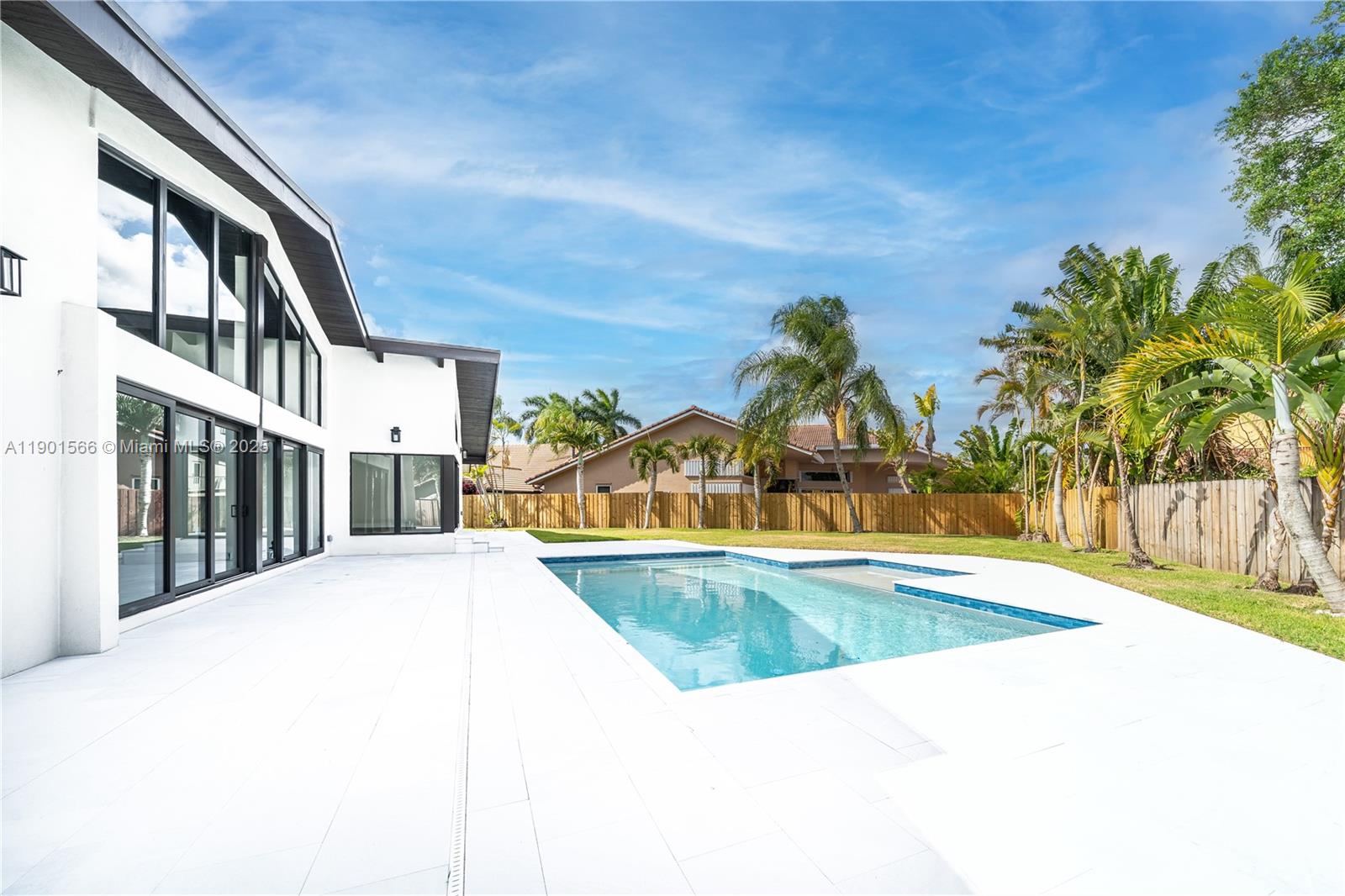 A modern white house exterior features a swimming pool and a patio in the backyard — 842 W Coco Plum Cir, Plantation FL 33324, PLANTATION, FL