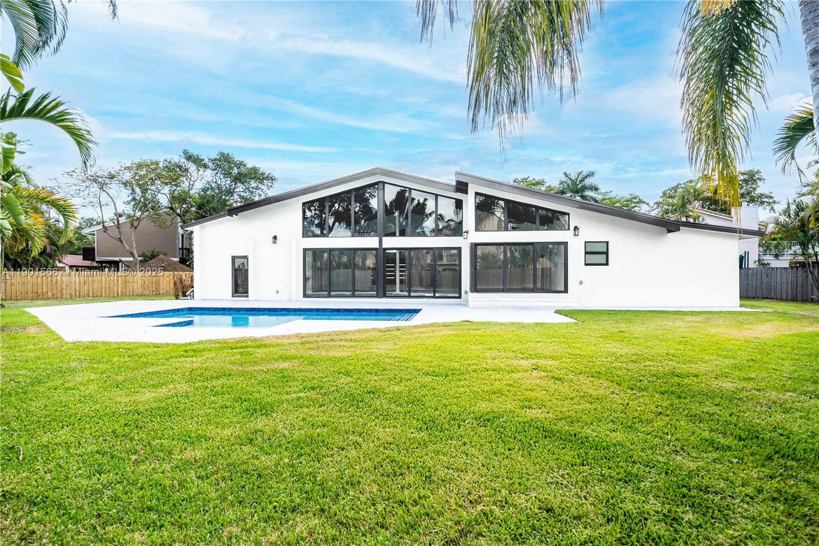 The exterior of a white house with large windows and a swimming pool in the backyard — 842 W Coco Plum Cir, Plantation FL 33324, PLANTATION, FL
