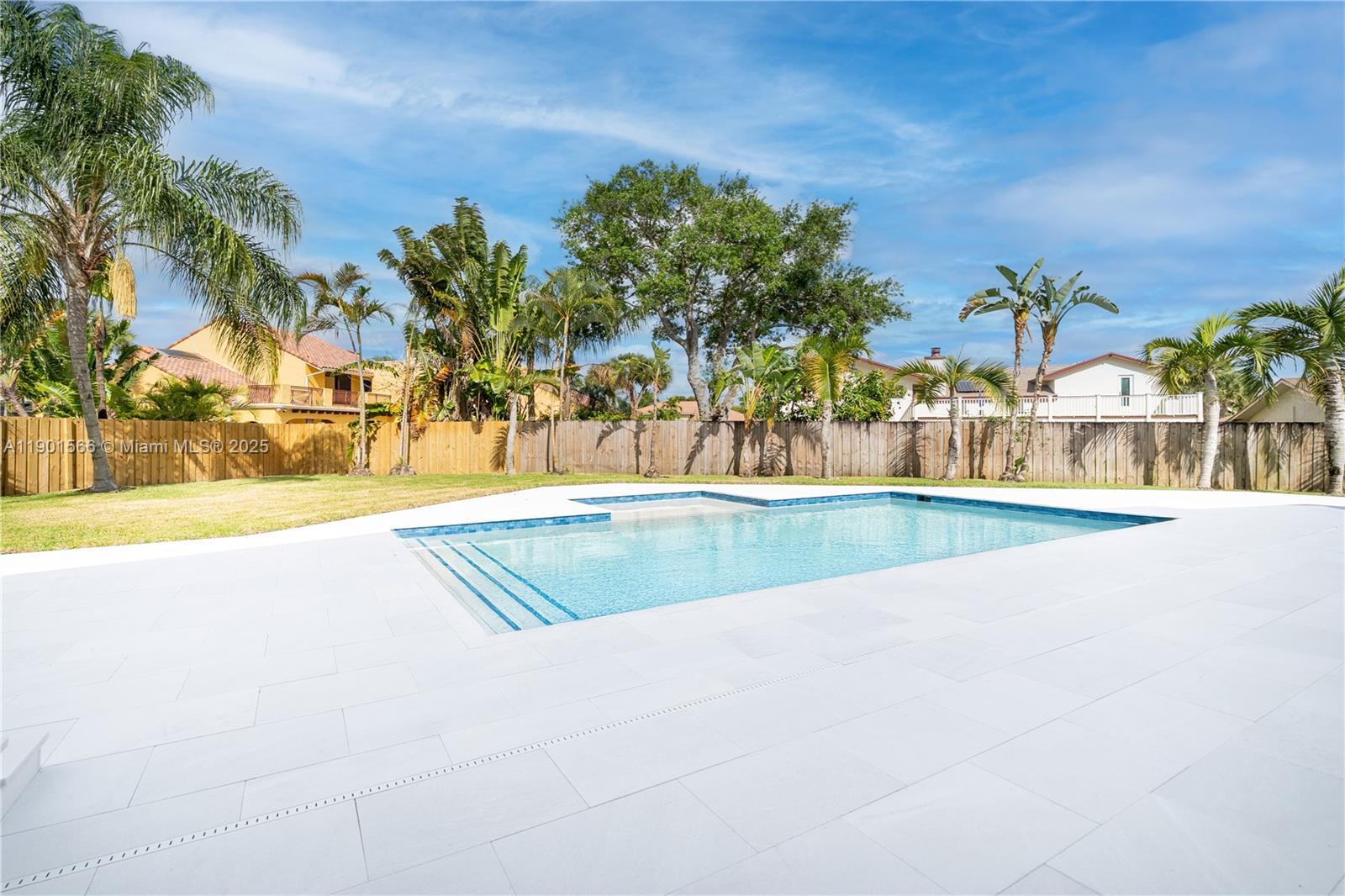 A backyard features a rectangular swimming pool surrounded by white pavers and a wooden fence — 842 W Coco Plum Cir, Plantation FL 33324, PLANTATION, FL
