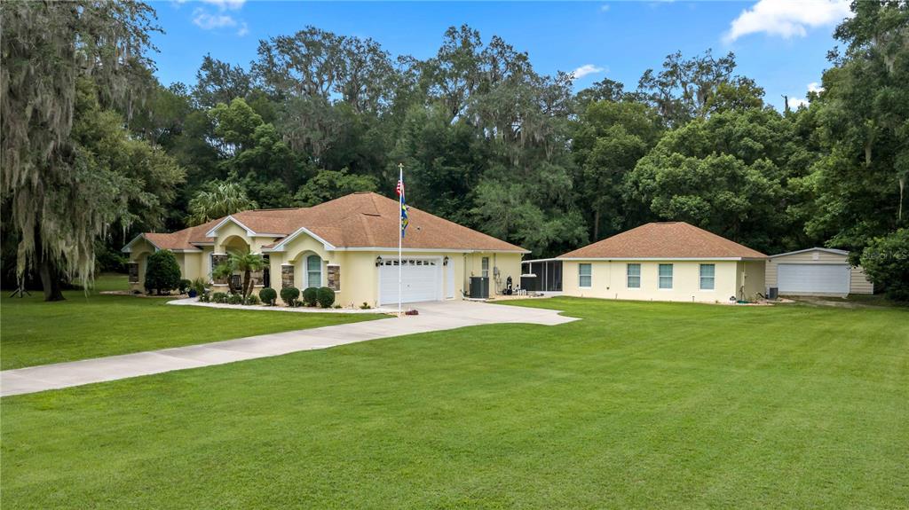 A single-story house with a tan exterior, a paved driveway, and a detached garage — 17261 SE 101ST AVENUE ROAD, SUMMERFIELD, FL