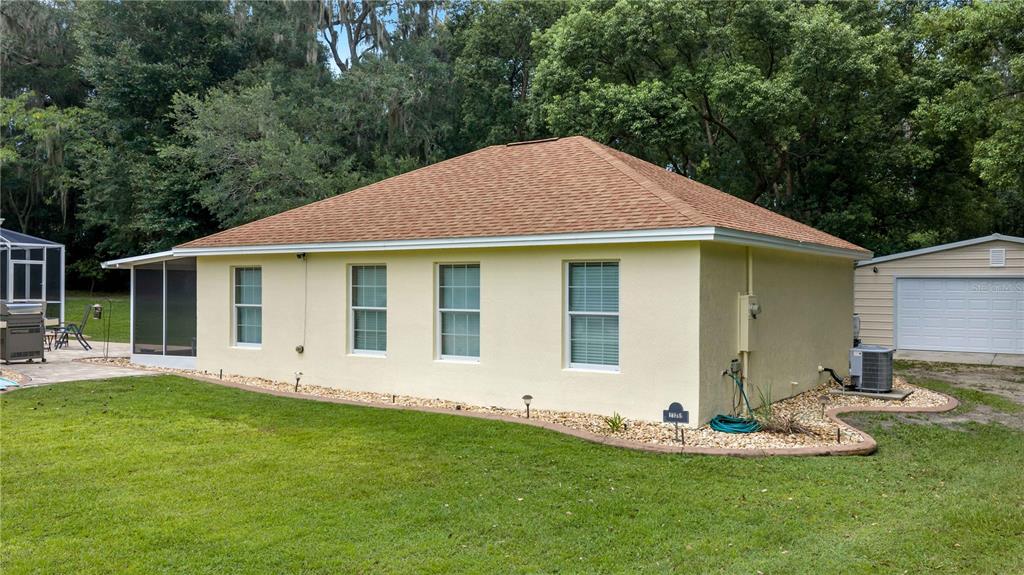 A yellow stucco house with a brown shingled roof and a detached garage — 17261 SE 101ST AVENUE ROAD, SUMMERFIELD, FL