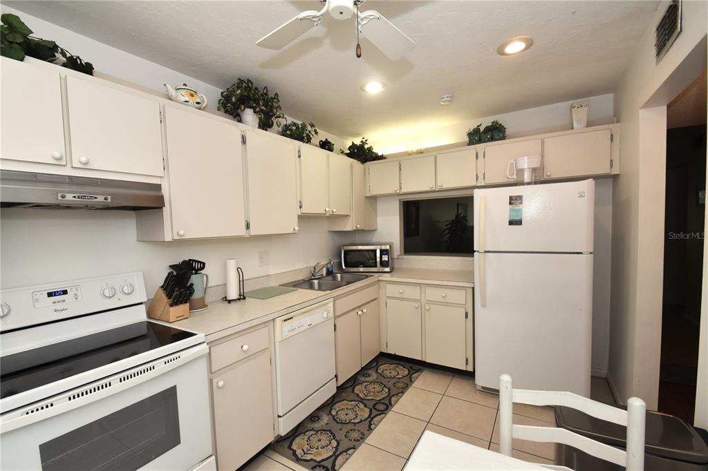 A kitchen with white cabinets, white appliances, tiled floors, and a ceiling fan — 1620 BOATHOUSE CIRCLE UNIT GR103, SARASOTA, FL