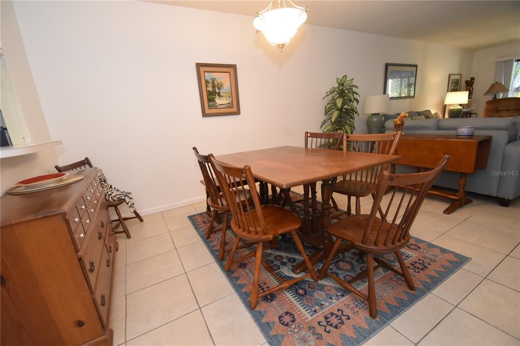 A dining area features a wooden table and chairs set on a patterned area rug — 1620 BOATHOUSE CIRCLE UNIT GR103, SARASOTA, FL