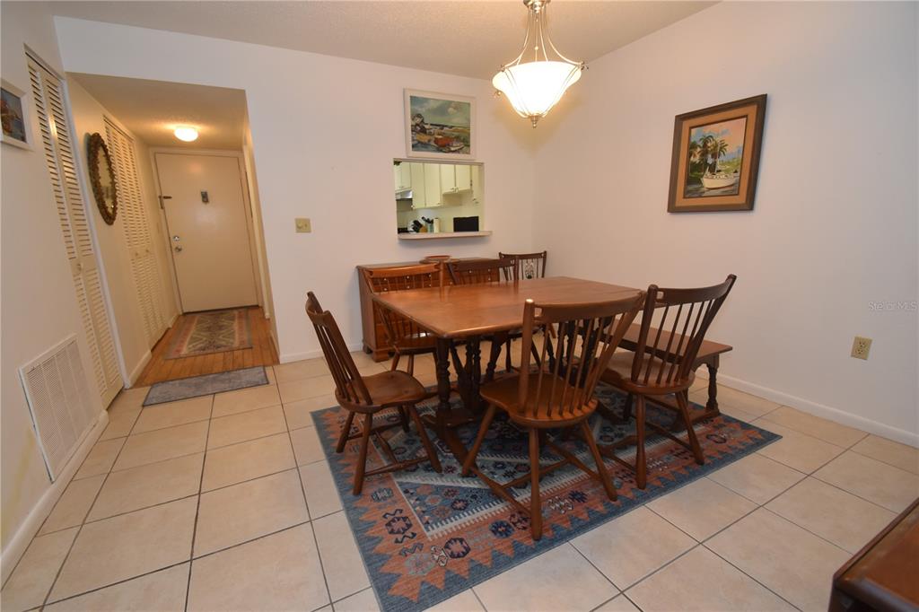 A dining room features a wooden table and chairs set on a patterned area rug — 1620 BOATHOUSE CIRCLE UNIT GR103, SARASOTA, FL