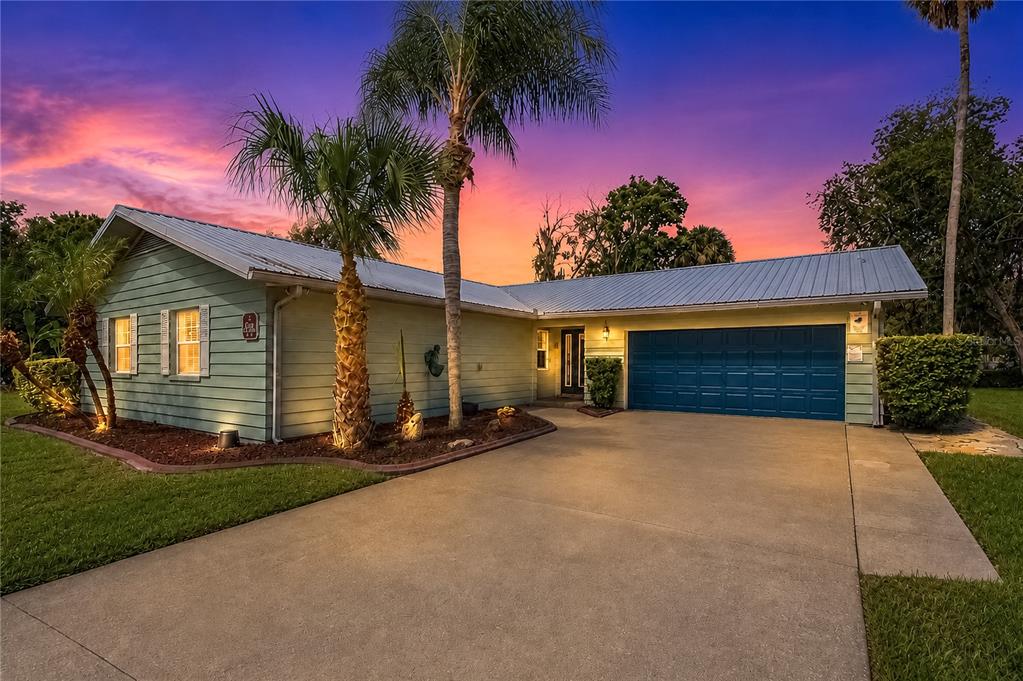 A single-story house with light green siding, a blue garage door, and a metal roof — 2178 N WATERSEDGE DRIVE, CRYSTAL RIVER, FL