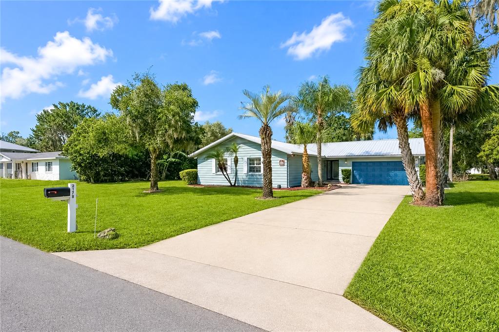 A light blue single-story house with a concrete driveway and palm trees in the front yard — 2178 N WATERSEDGE DRIVE, CRYSTAL RIVER, FL