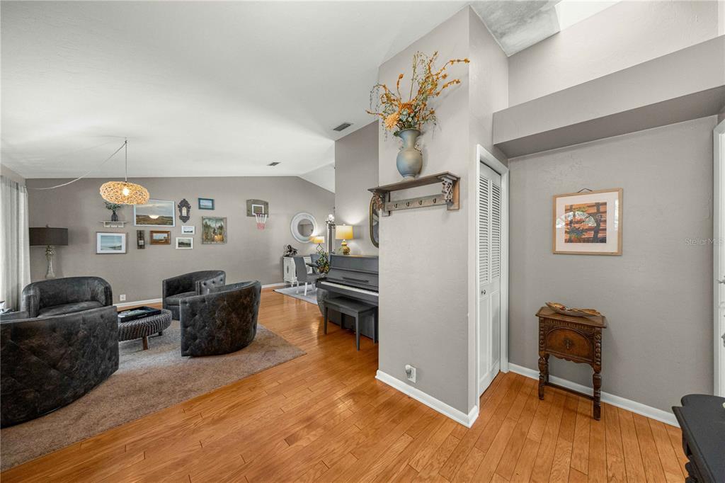 A living room with hardwood floors, a piano, and a gallery wall of framed pictures — 4312 NW 12TH PLACE, GAINESVILLE, FL