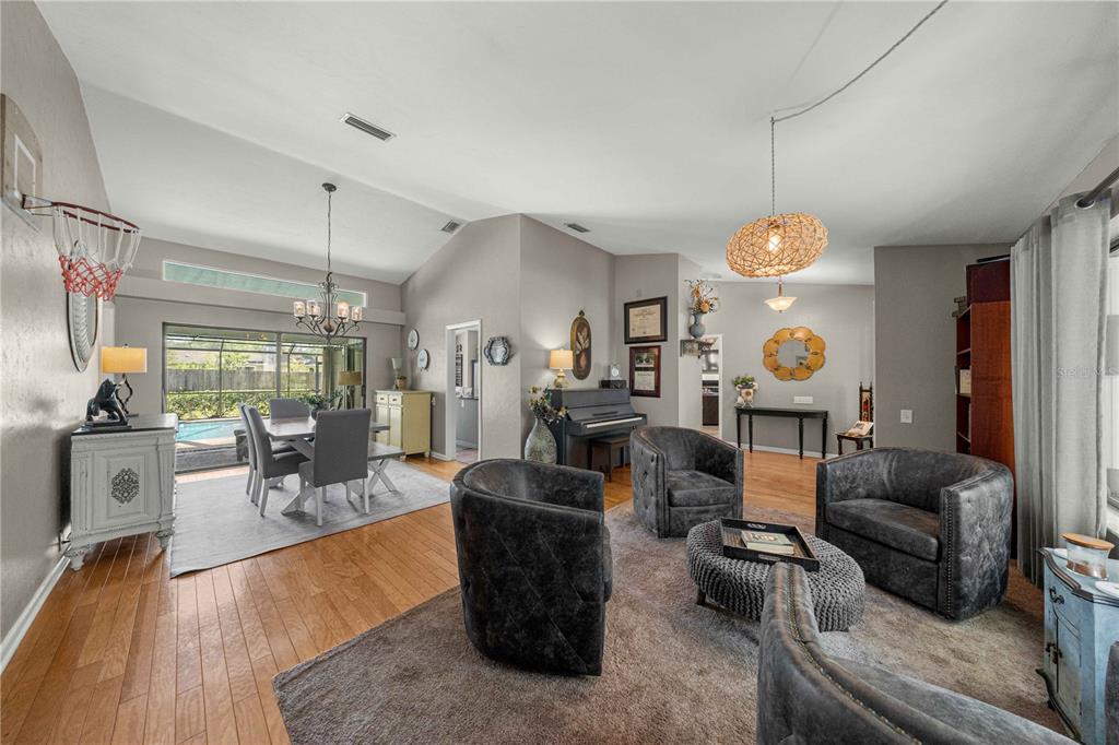 A living and dining area with hardwood floors, a piano, and a view of a pool — 4312 NW 12TH PLACE, GAINESVILLE, FL