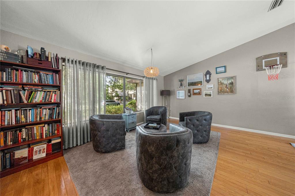 A living room features a bookshelf, four tufted chairs, a rug, and a basketball hoop — 4312 NW 12TH PLACE, GAINESVILLE, FL