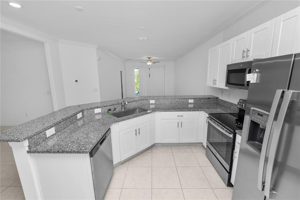 A kitchen with white cabinets, granite countertops, and stainless steel appliances — 6851 RIPPLE POND LOOP, ZEPHYRHILLS, FL