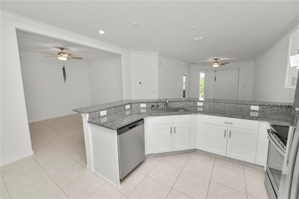 A kitchen with white cabinets, granite countertops, stainless steel appliances, and tile flooring — 6851 RIPPLE POND LOOP, ZEPHYRHILLS, FL